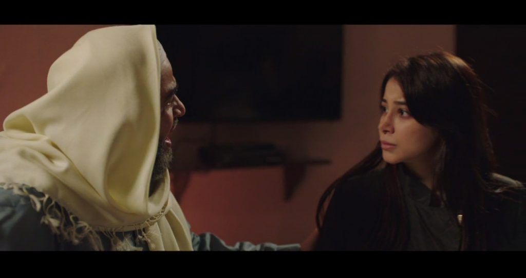 Abu ʿUmar (left, portrayed by Rashid Al Shamrani), who acts as an informal narrator, confronts his daughter Amal (right, portrayed by Aseel Omran), who was kidnapped by her husband, an ISIS fighter, and taken to Syria.